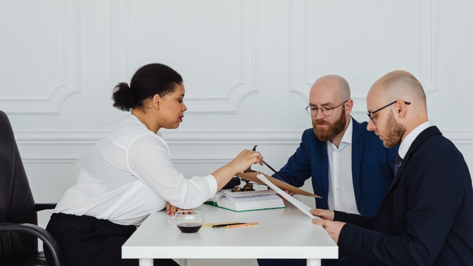 Professionals reviewing commercial dispute documents at a meeting table with scales of justice